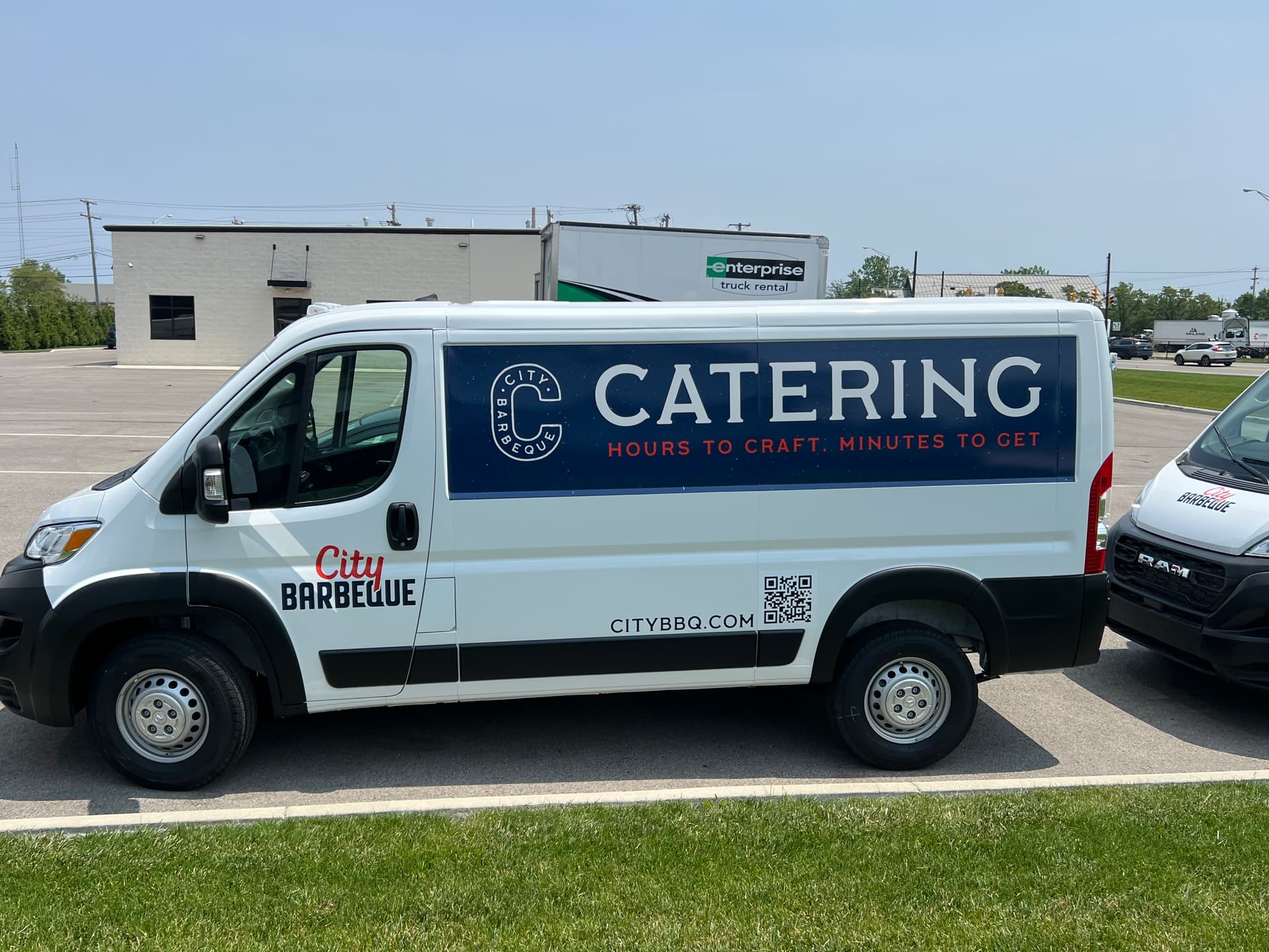 White Ram ProMaster van in full catering livery with a QR code, parked outside a commercial building