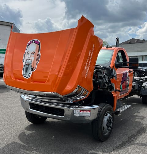 Orange work truck with a hand-lettered logo, phone number and web address applied to the hood and fender