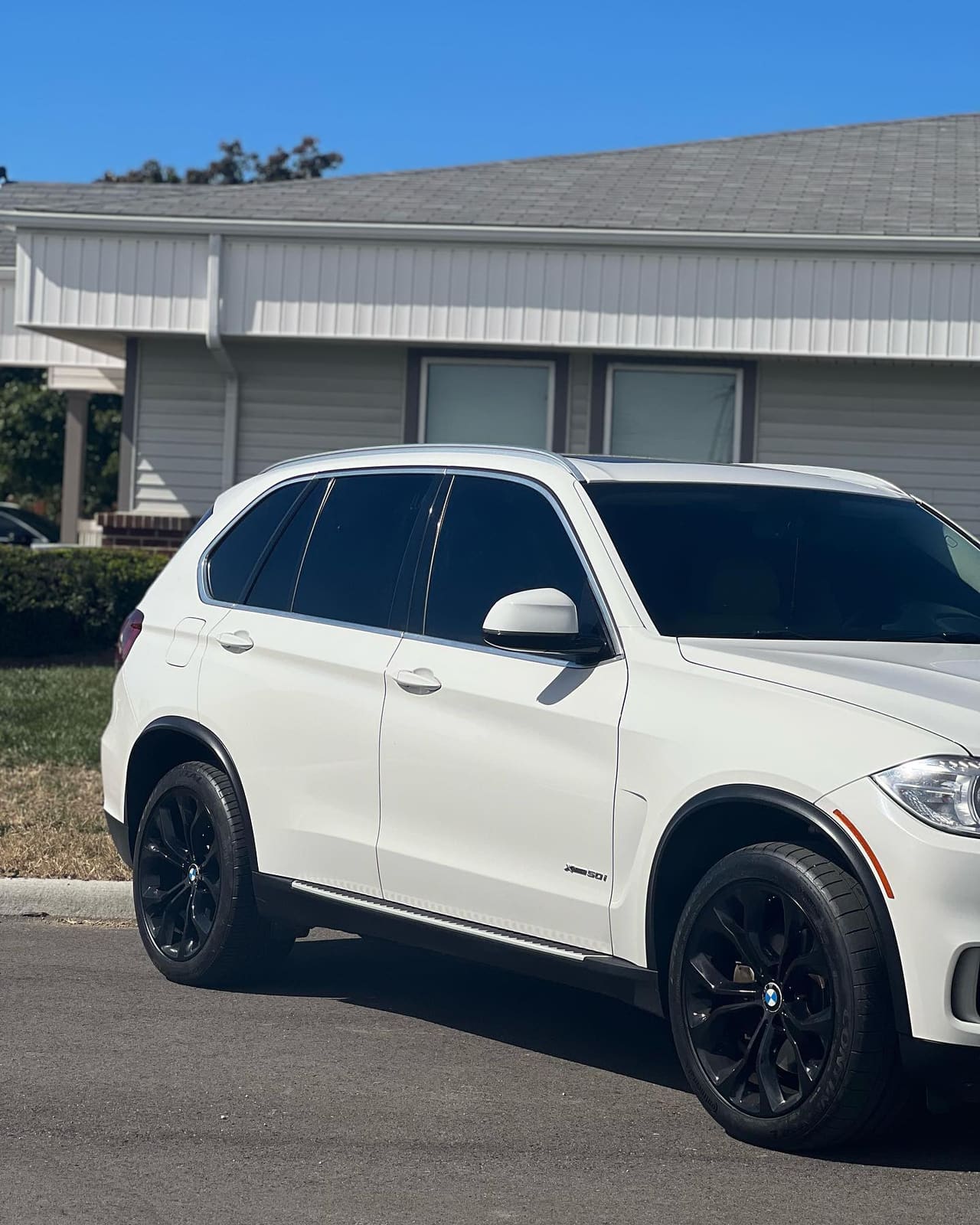White BMW X5 in side profile with dark tinted windows and gloss black wheels