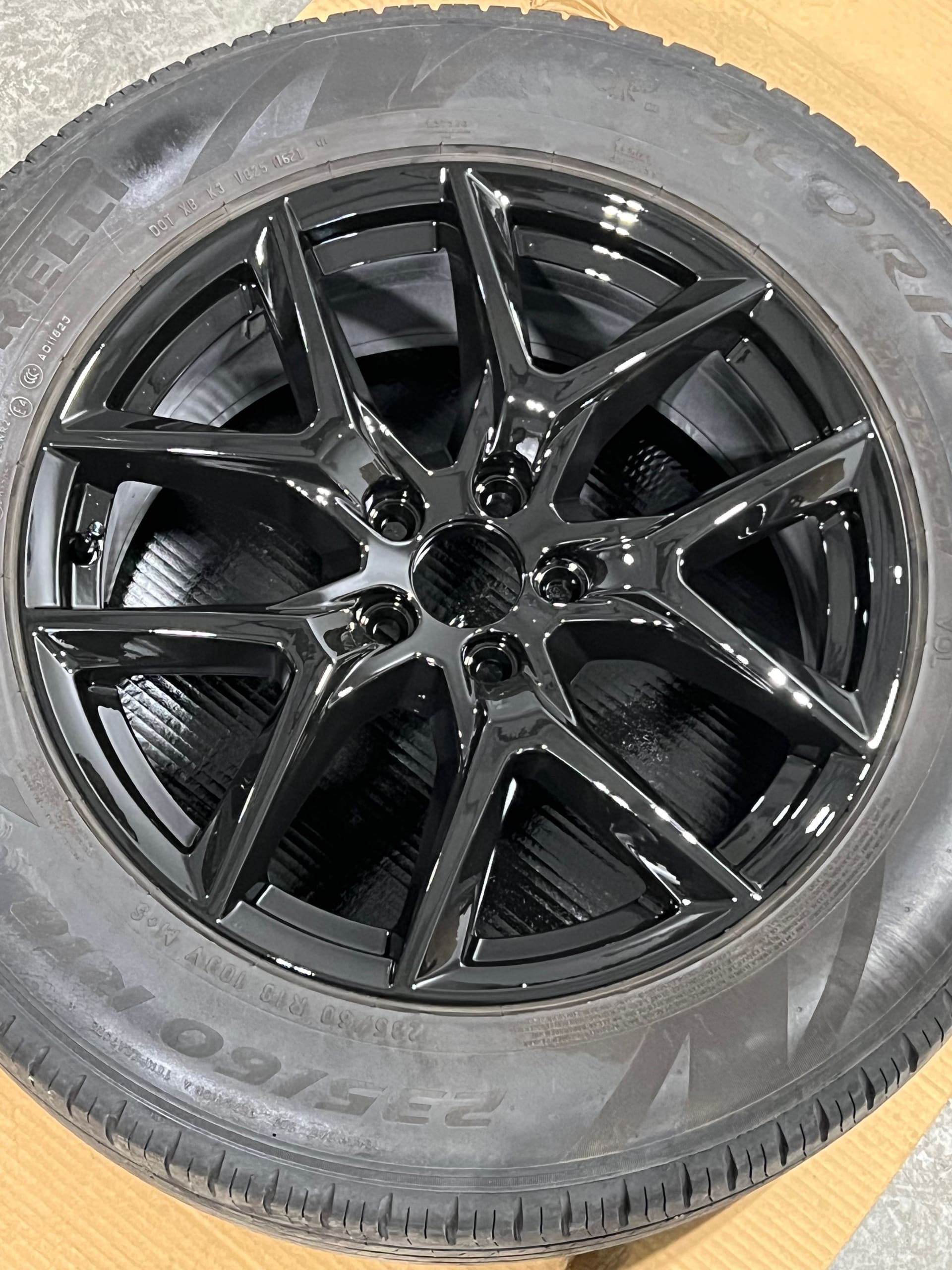 A finished gloss black multi-spoke alloy wheel on a Michelin tyre, photographed from above