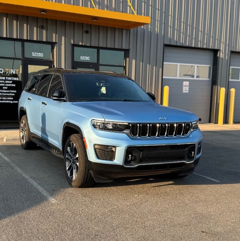 Blue Jeep Grand Cherokee L parked in front of the Mo Tint storefront at golden hour, unit numbers 5220D and 5220C legible on the doors under a yellow awning