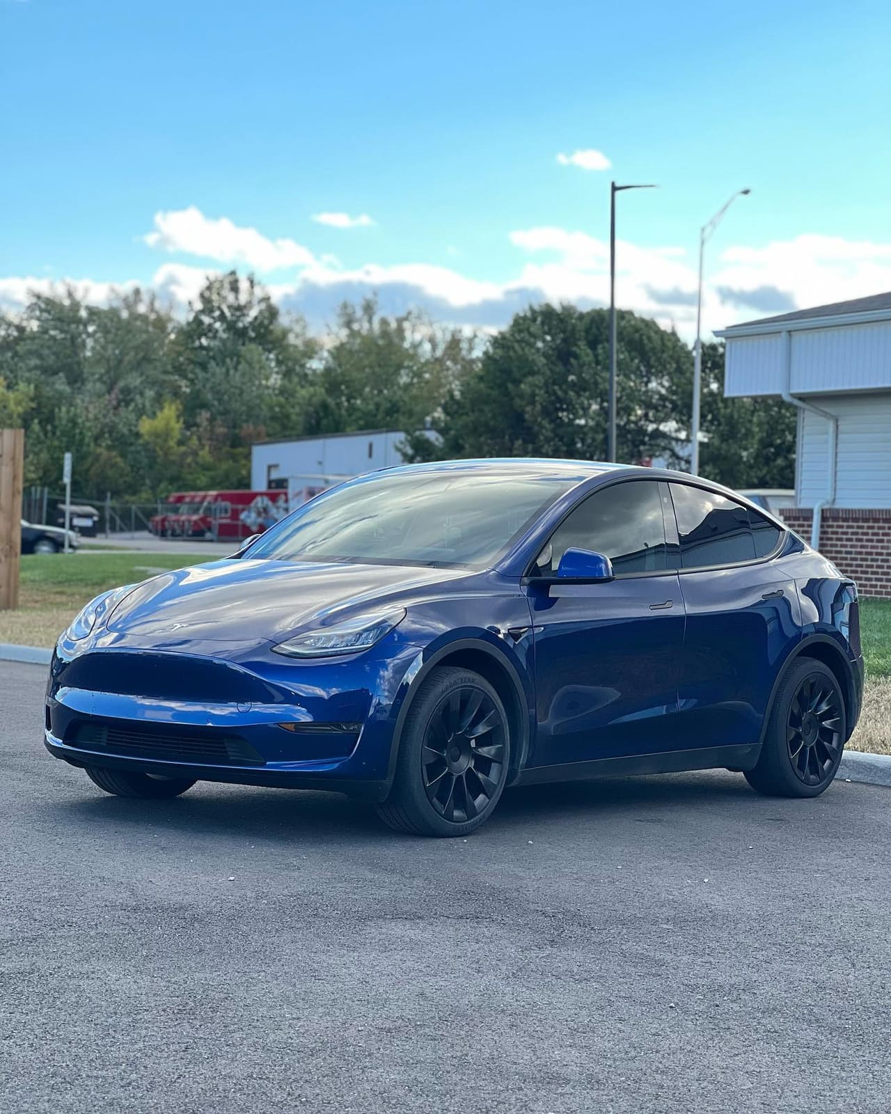 Deep metallic blue Tesla Model Y with dark tinted glass all round, photographed in low golden sun