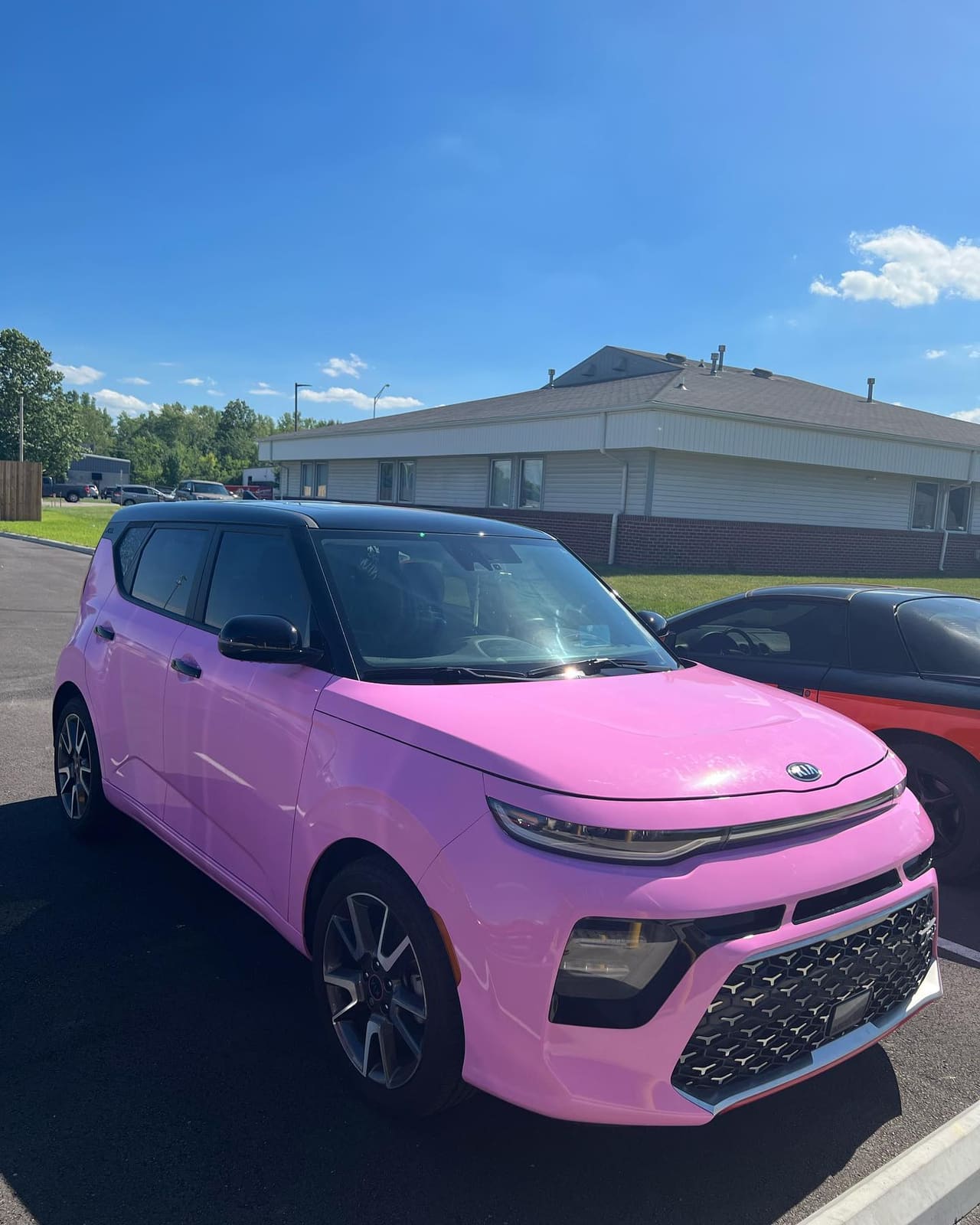 Bright pink Kia Soul in a full colour-change wrap, front three-quarter in sunlight
