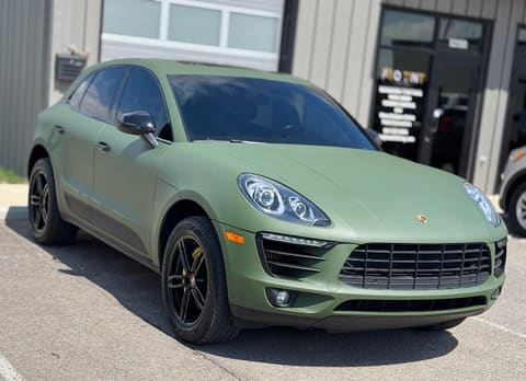 Porsche Macan in matte army green wrap parked outside the shop, yellow calipers behind gloss black wheels
